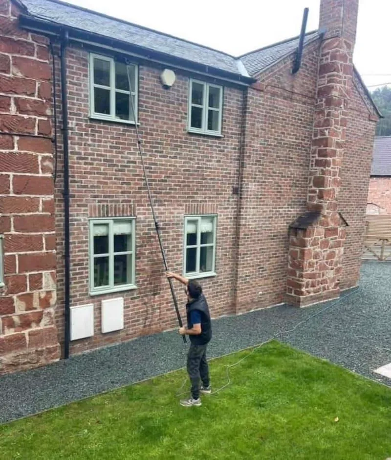 Hot water-fed pole cleaning an upstairs window in Telford, streak-free glass